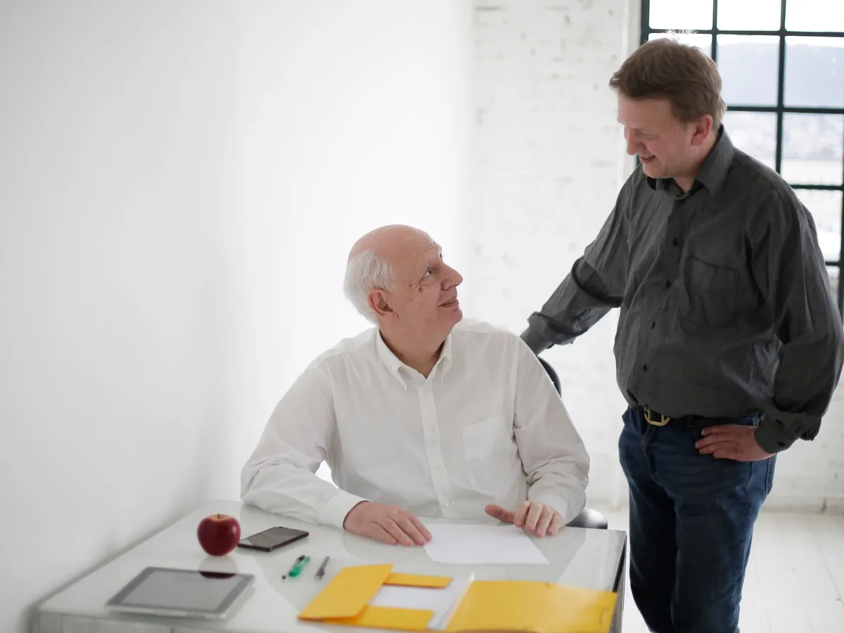 Collega legt een hand op de schouder van een medewerker aan zijn bureau